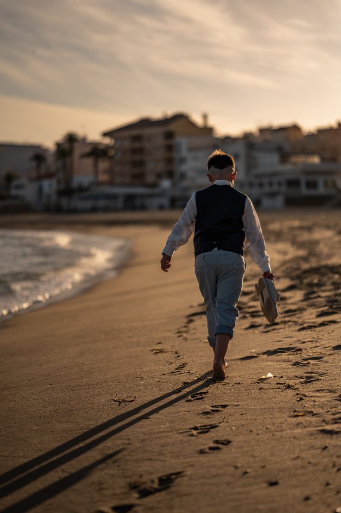 Niño caminando hacia el atardecer durante una sesión de fotos de comunión en exterior en Garrucha